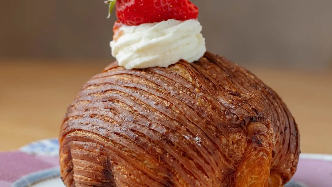 A laminated pastry dome topped with cream and a strawberry at Bap