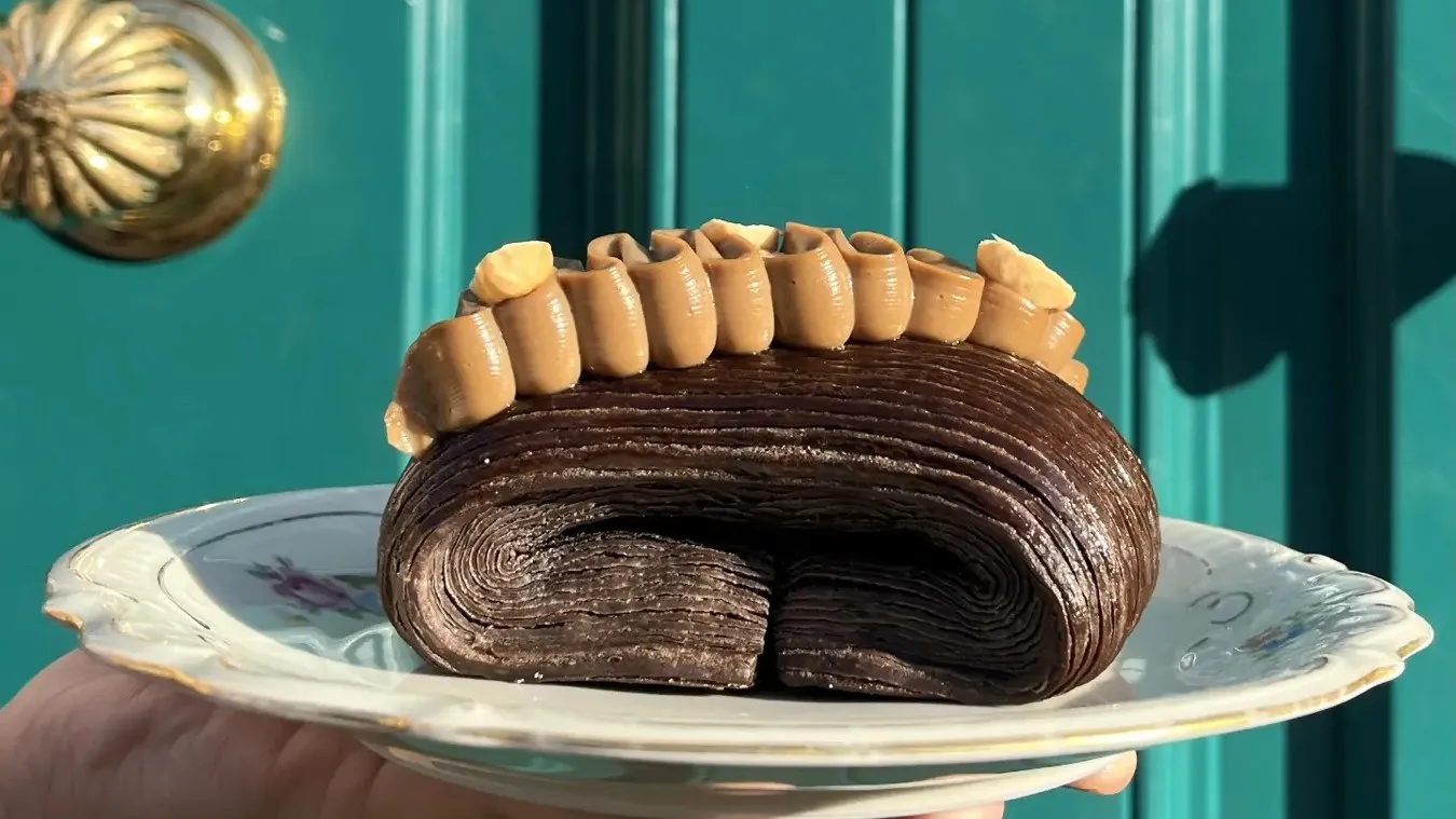 A pain suisse with gianduia and coffee ganache, held up on a plate