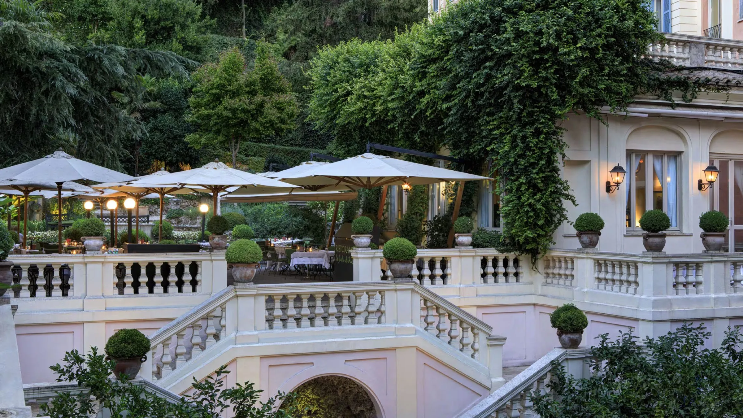 The terraced garden at Le Jardin, umbrellas and balustrades below an ivy covered facade