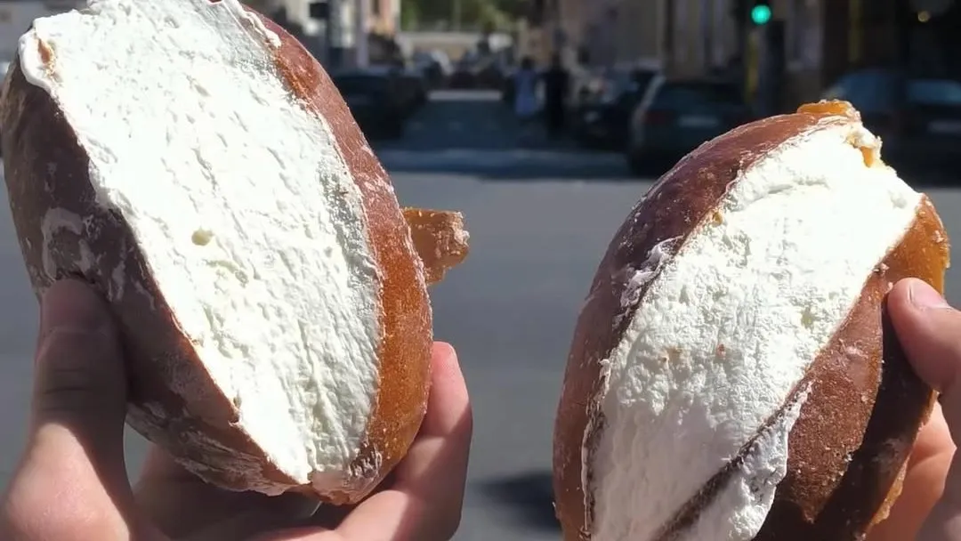 Two maritozzi packed with cream held up in the street outside Il Maritozzaro