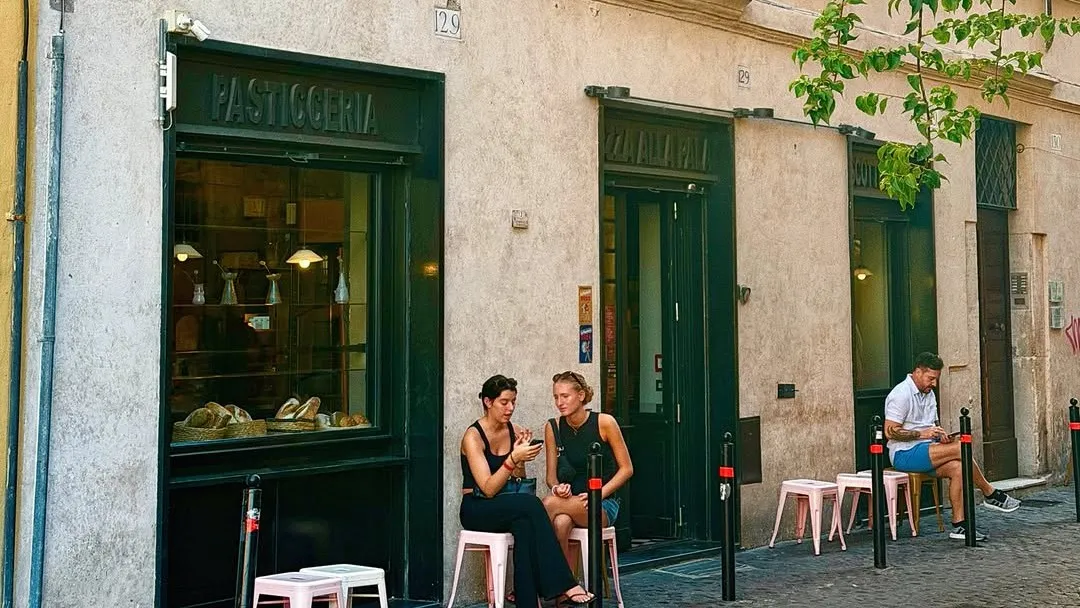 The front of Forno Monteforte on Via del Pellegrino, with people at small tables outside