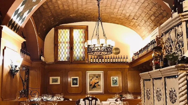 The vaulted brick ceiling and wood-panelled walls of Girarrosto Fiorentino, with a wrought-iron chandelier