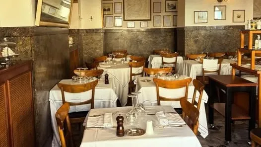 The historic dining room at La Matriciana, with framed pictures on the walls and tables set in white